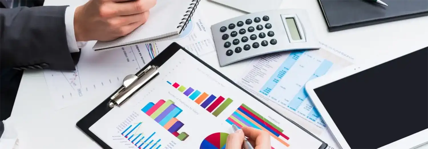 Directeur comptable de transition analysant des graphiques financiers, des états comptables et des reportings avec une calculatrice et une tablette.