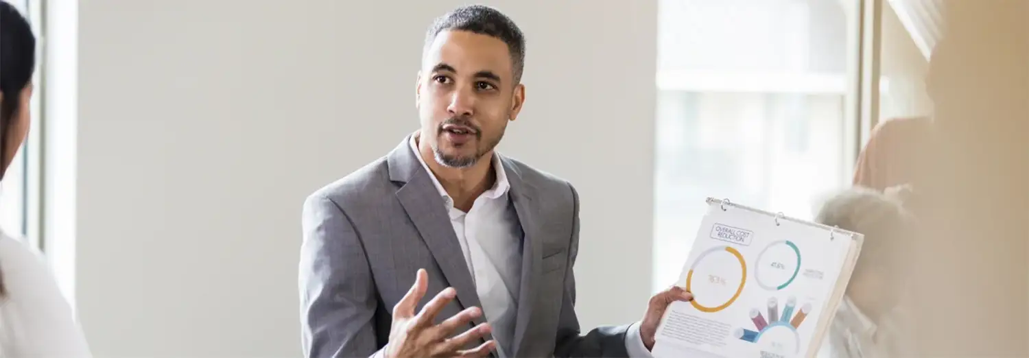 Directeur commercial de transition présentant des indicateurs de performance et des résultats commerciaux lors d’une réunion.