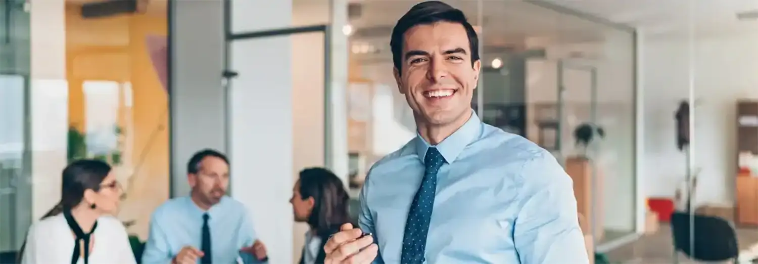 Directeur de filiale de transition souriant, incarnant le leadership et la gestion stratégique, en réunion avec son équipe pour piloter le développement et la performance de l’entreprise.